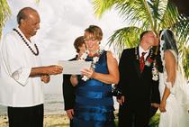 Bride and groom kissing as Reverend Bill helping mom sign the certificate