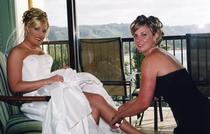 maid of honor putting garter on seated bride